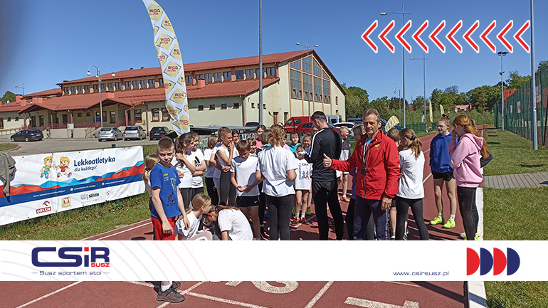 Zdjęcie przedstawiające dzieci biorące udział w zawodach z koordynatorem Suskich Czwartków Lekkoatletycznych - Andrzejem Szyslerem