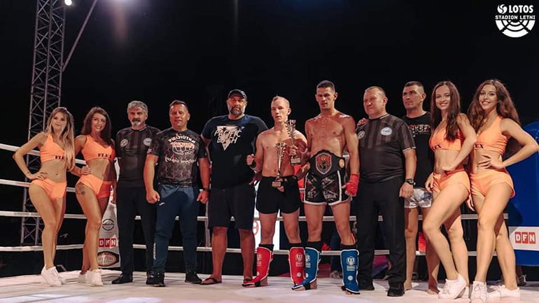 Mateusz Leński na ringu wraz z trenerami i uczestnikami turnieju
